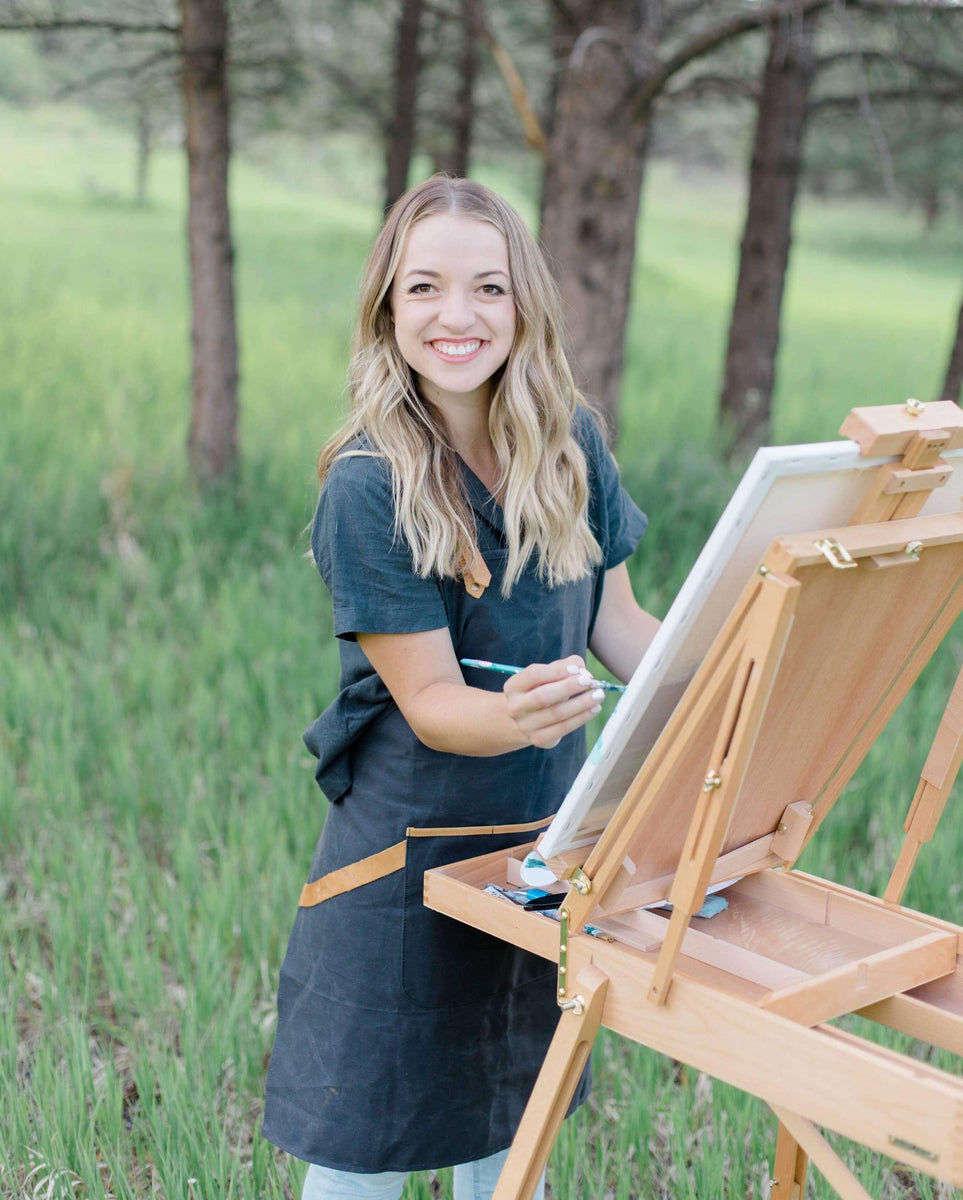 Meg Elaine Miller (artist) headshot painting with an outdoor french easel