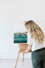 Load image into Gallery viewer, Artist adding in final details on a fine art mountain painting, resting on an easel.
