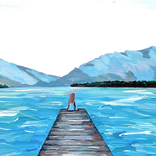 Girl sitting on the end of a dock print of a fine art painting with blue mountains and a white sky.  This print is designed to inspire travel and wanderlust.
